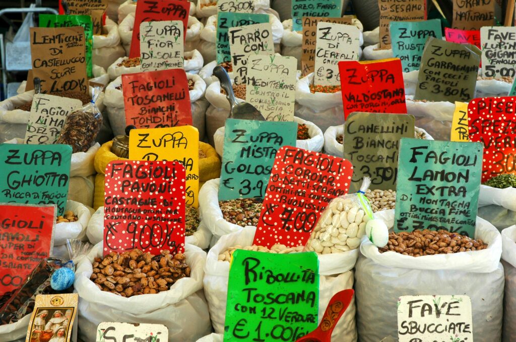 pexels-photo-1024005-1024005 Vibrant assortment of beans and lentils in a Roman market, featuring colorful labels and diverse varieties.