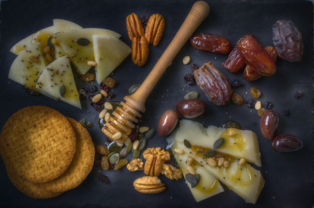 pexels-photo-1152276-1152276 A delightful snack assortment with cheese slices, nuts, dates, and honey on a slate board.