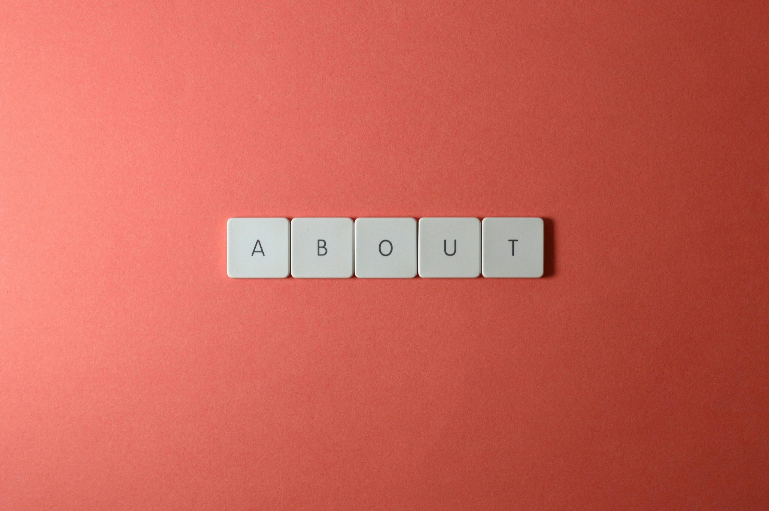 pexels-photo-2882509-2882509 Close-up of keyboard buttons spelling 'ABOUT' against a red surface, minimalist style.