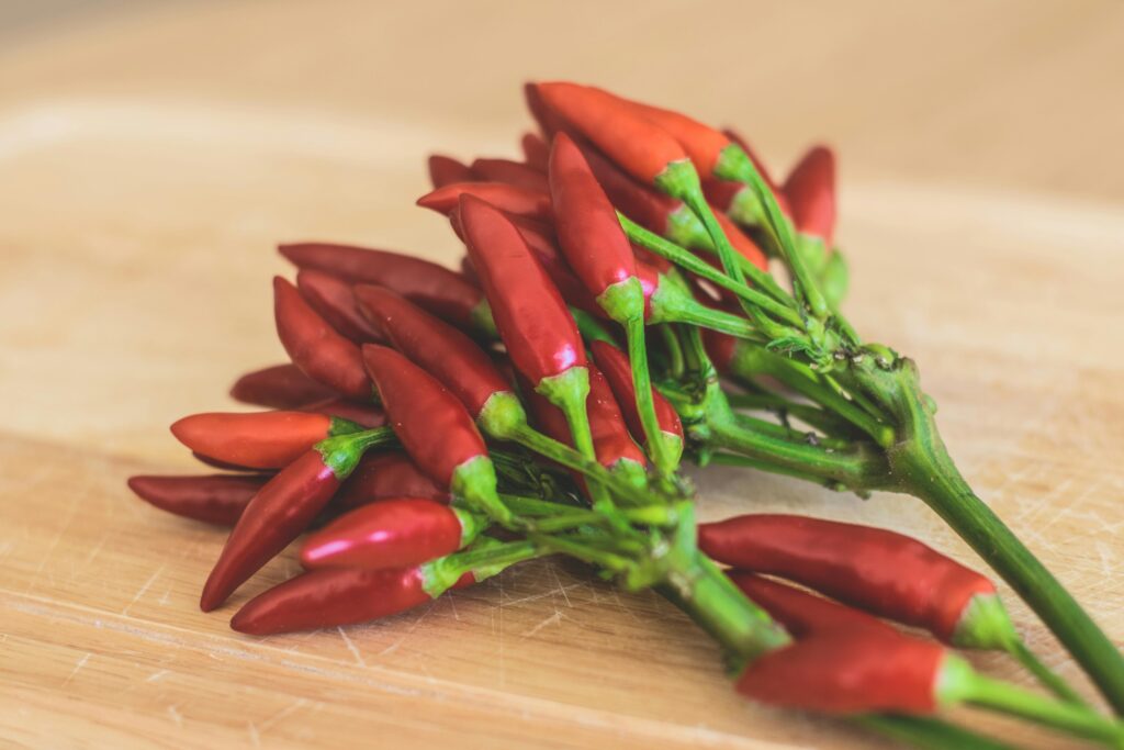 Close-up of vibrant red chili peppers arranged on a wooden cutting board, perfect for spicy dishes.