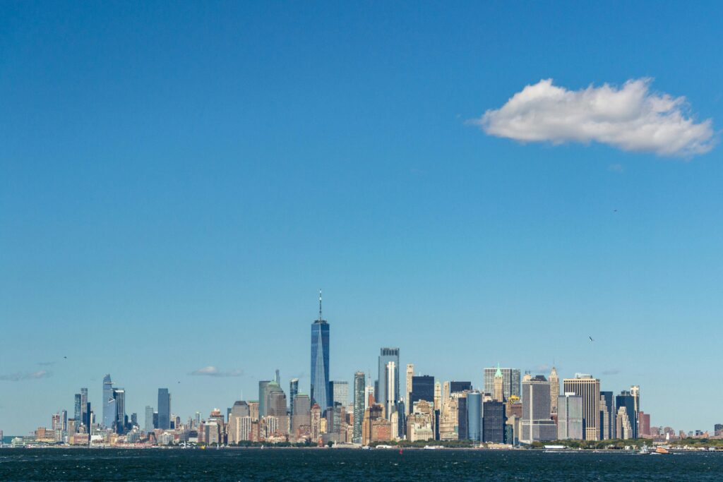 Stunning view of New York City skyline featuring the iconic One World Trade Center under a clear blue sky.